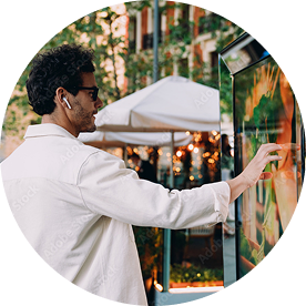 Man in white shirt using outdoor digital kiosk touchscreen with wireless earbuds